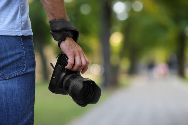 istock Photographer with professional camera in park, closeup 1388754478
