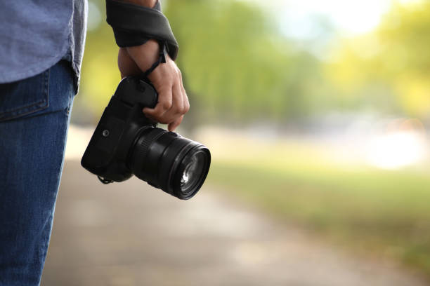 istock Photographer with professional camera in park, closeup 1388754517