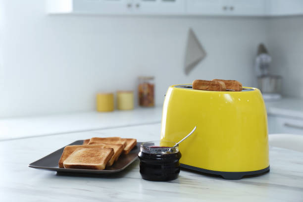 istock Modern toaster with slices of bread and jam on white marble table in kitchen 1388755190