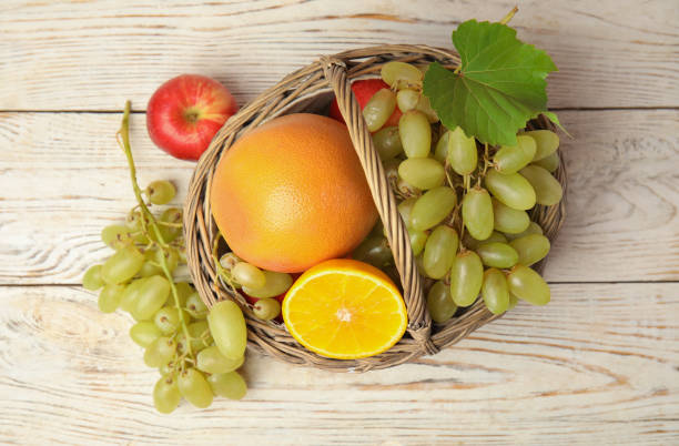 istock Wicker basket with different fruits on white wooden table, flat lay 1388755764