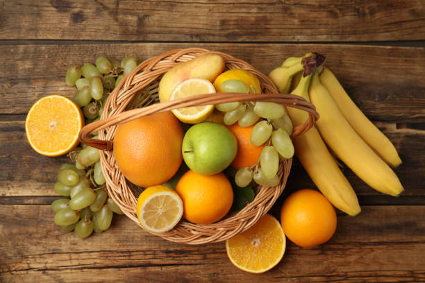 istock Wicker basket with different fruits on wooden table, flat lay 1388755886
