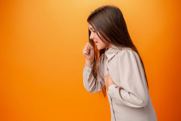 adolescente con ropa casual que se siente mal y tose contra fondo naranja - cough remedy fotografías e imágenes de stock