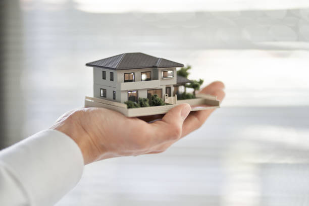 Hands of an Asian man holding an architectural model of a single house stock photo