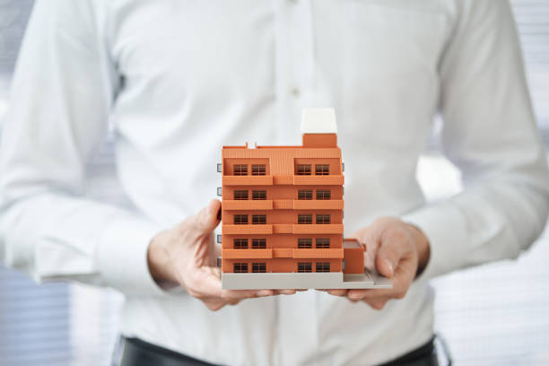 アパートの建築模型を持つアジア人男性の手 - 集合住宅 ストックフォトと画像
