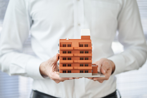 Hands of an Asian man holding an architectural model of an apartment