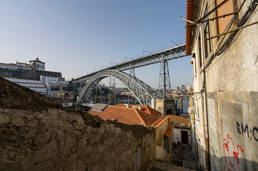 Porto, Portugal. March 2022. a typical street between the old houses of the city center that goes down towards the river with the Dom Luís I iron bridge in the background