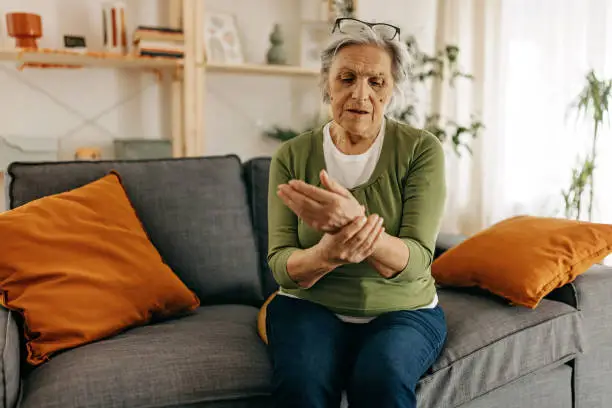 Senior woman feeling wrist and hand pain, osteoporosis problems