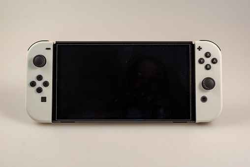 Hamburg, Germany- 03302022: closeup of a nintendo switch console O-LED model with white joy-cons against a light background