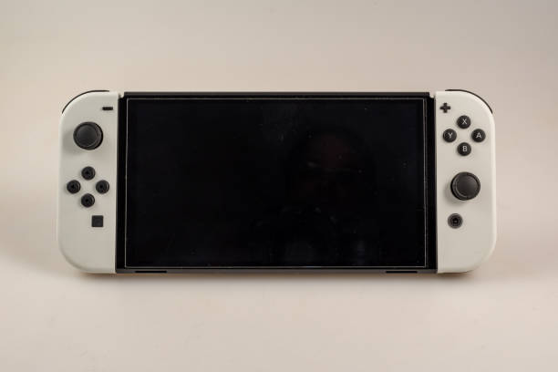 Nintendo Switch O-LED Model Hamburg, Germany- 03302022: closeup of a nintendo switch console O-LED model with white joy-cons against a light background switch stock pictures, royalty-free photos & images