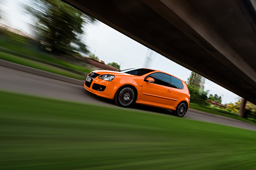 Kyiv, Ukraine - June 20 2016: motion shot of orange Volkswagen Golf GTi mk5. Driving fast on narrow road