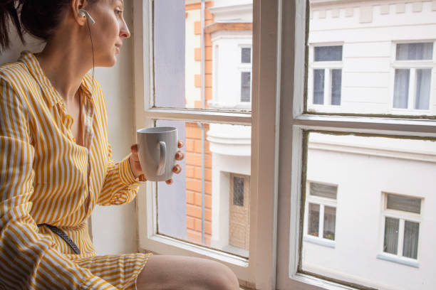 istock Young woman sitting and looking through window 1388779557