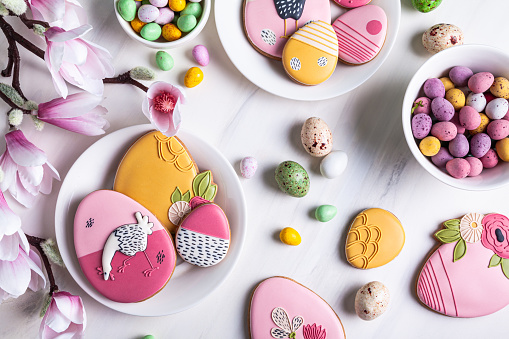 Handmade Easter gingerbread cookies and chocolate eggs on a white plate on a white  background.