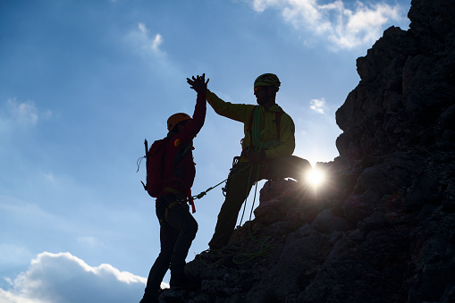 Two climbers helping each other to the top of the mountain.