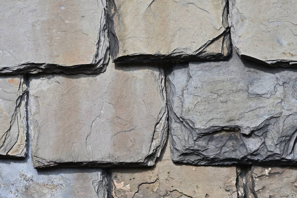 Slate roof shingles close-up in sunlight, with shadows