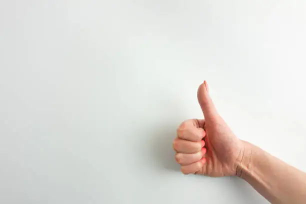 Photo of Female palm making thumbs up gesture. Woman's hand is isolated on white background