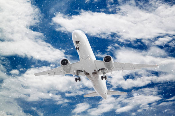 istock white passenger plane has released its landing gear and is landing through falling snow against background of beautiful white clouds on blue sky 1388785947