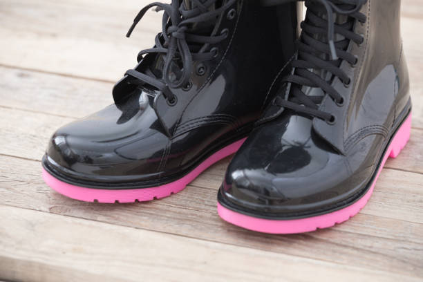 Pair of pink colored kids rubber boots on wood background