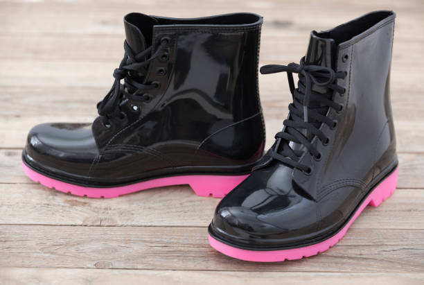 Pair of pink colored kids rubber boots on wood background