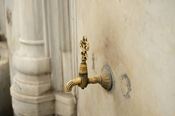 A woman washing her hands at a historical ottoman fountain. Istanbul Turkey