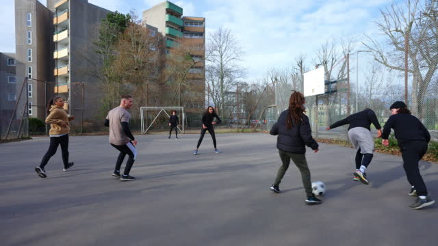 Diverse group of friends playing football during weekend in the city