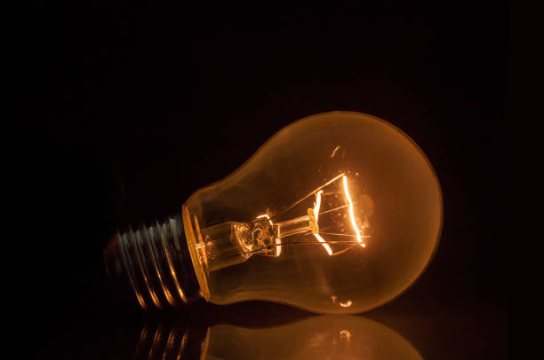 istock Glowing retro light bulb close up on black background 1388798953