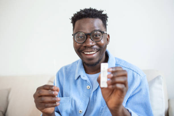 istock African-American man holding a negative test device. Happy young man showing his negative Coronavirus - Covid-19 rapid test. Coronavirus 1388800235