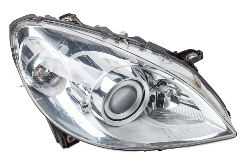 Stylish xenon headlight of a German car - optical equipment with a lamp inside on a white isolated background. Spare part for auto repair in a car workshop.