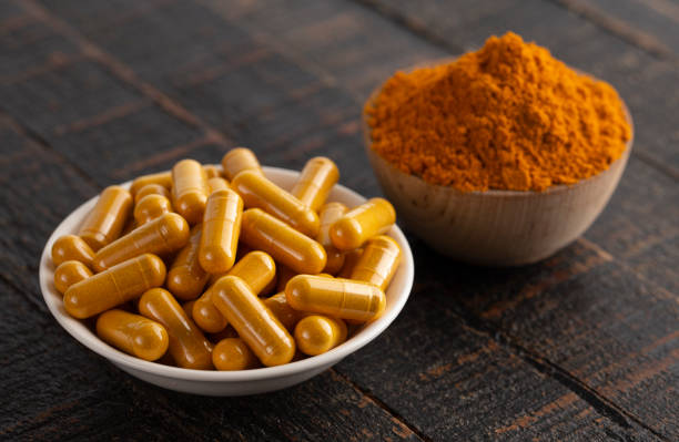 istock Ground Turmeric in Capsule form on a Dark Wooden Table 1388803308