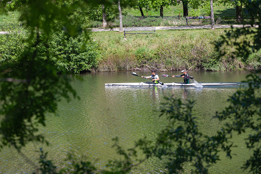 Plasencia, Spain - April 18, 2021: Two young women practice anoeing riding in his canoe navigating the Jerte river