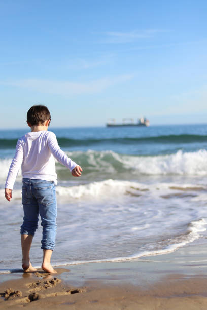 istock Boy playing on a beach with his pants rolled up 1388808212