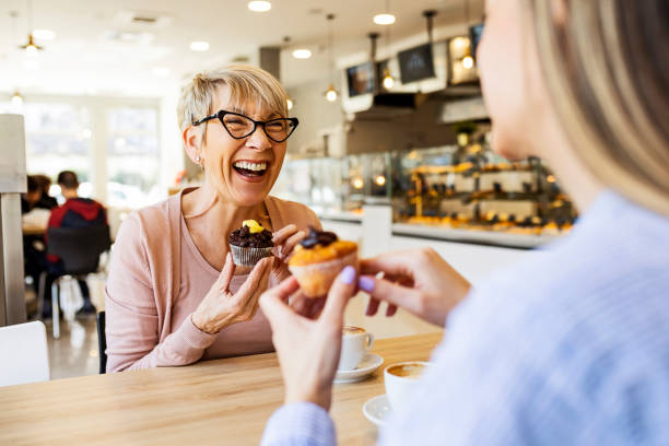 カップケーキとコーヒーを飲みながら話す笑顔の女性 - whoopee pie ストックフォトと画像
