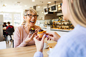 Smiling women talking over cupcake and coffee