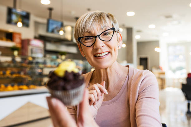 istock Senior woman eating cupcake looking at camera 1388809281