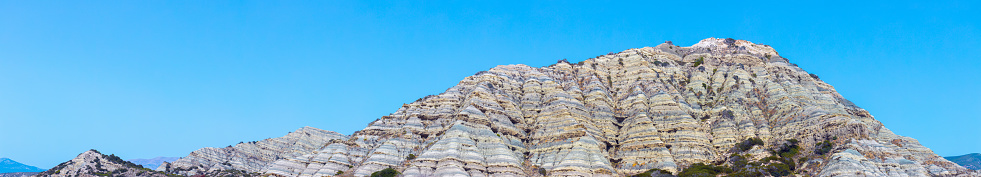An exciting panoramic view of amazing an interesting mountain that is like a pie of sedimentary, rocky and limestone rocks at southern Rhodes, Greece. Sunny hot weather in mid-July.