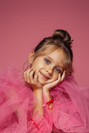 Cute little girl in orange dress posing over white background. Little princess girl portrait