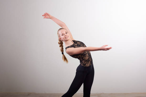 Portrait of ballerina dancing against wall in studio stock photo