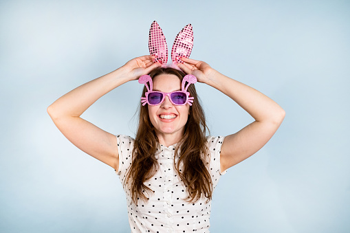 Woman smiling, holding her pink bunny ears.