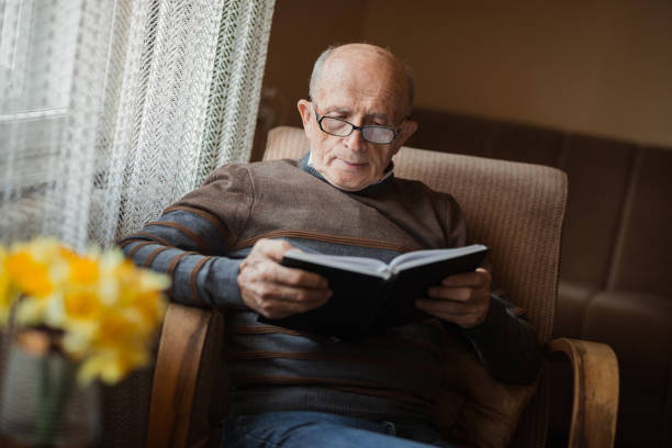 istock Elderly man reading a book curiously 1388819828