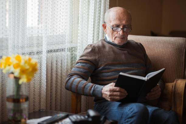 istock Senior man concentrating on a book in his hands 1388819839