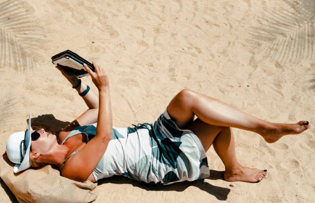 istock Woman reading online book at the beach 1388819865
