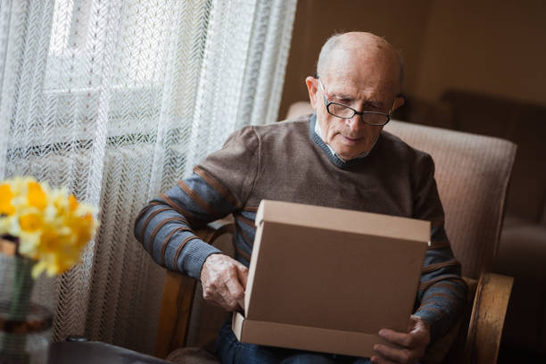 istock Old man holding a gift box in his hands 1388819876