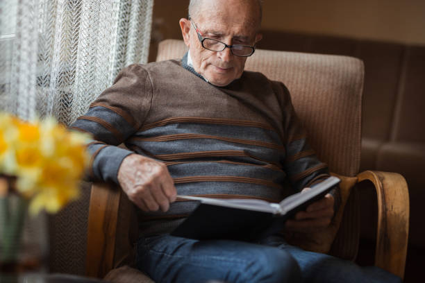 istock Old man sitting at home and reading an inspiring book 1388819880