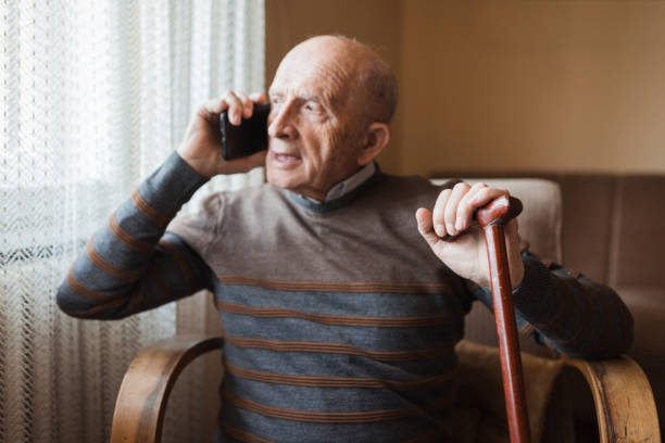 istock Man leaning onto walking cane when sitting and talking via mobile phone 1388819936