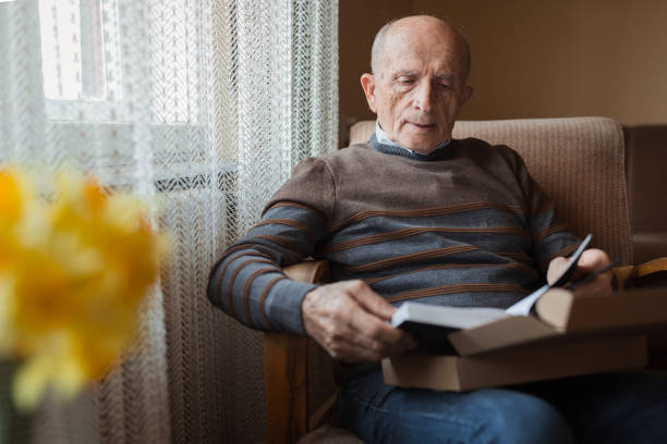 istock Senior man inspecting the book he just unboxed 1388819941