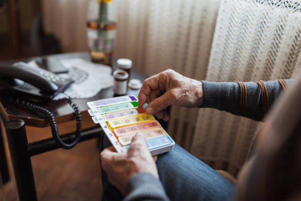 Senior man putting medications in a pill organizer, close up