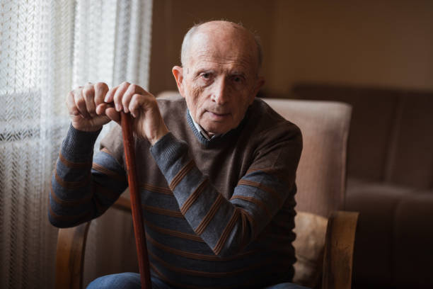istock Senior man sitting and bending over a walking cane 1388820017