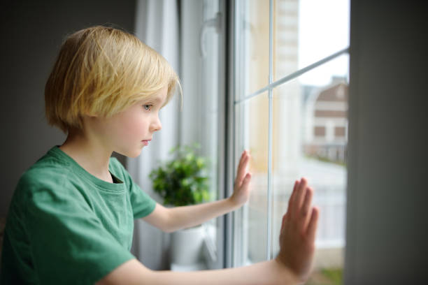 istock Sad little boy sitting near window and watching street. Post-traumatic disorder. Accommodation of grief. Experiencing loss. Fear. Depression. Stress. Upset kid 1388820663