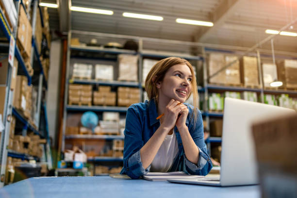 Woman using laptop at warehouse stock photo