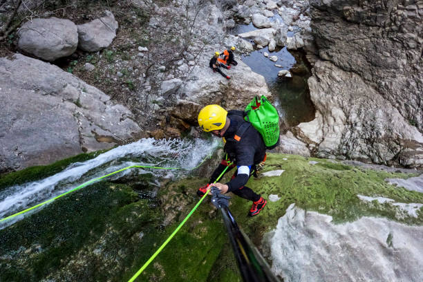 Extreme canyoneering team member seen directly from above while rappelling down a beautiful waterfall during a spectacular adventure in the untouched nature.