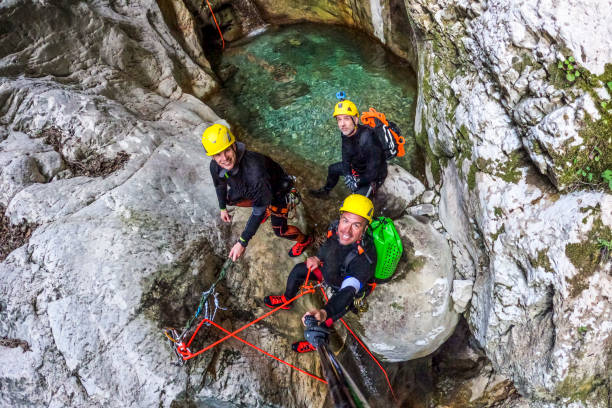 Friends seen in the magical canyon while enjoying extreme canyoning adventure Three canyoneering team members seen directly from above while smiling and enjoying in the spectacular canyon in the untouched nature during their extreme canyoning adventure. canyoneering stock pictures, royalty-free photos & images